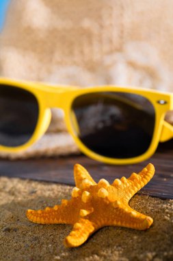 Bir yaz şapkası ve güneş gözlüğü sahilin kumlu sahilinde uzanıyor..