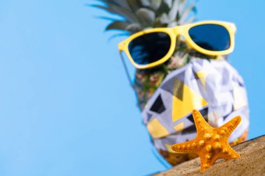 Olgun ananas. Koruyucu maske. Sarı çerçeveli güneş gözlüğü. Deniz sahili. Güneşli bir gün.