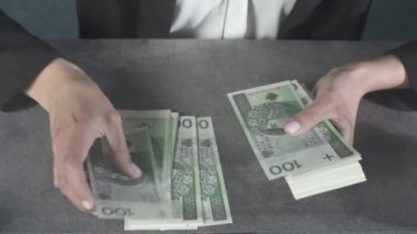 Kadın elinde kalın bir deste banknot tutuyor ve saymaya başlıyor. Genç kadınların yeni 100 zloti banknotlar halinde nasıl büyük miktarda para saydıklarına dair yakın plan bir bakış..