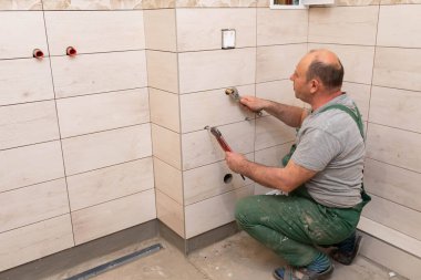 Tesisatçı pisuarın kurulumu için su girişlerini düzenlemeye başladı. Hidrolik endüstrisinden bir çalışan..