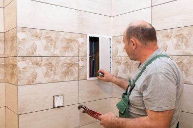 Bir çalışan banyodaki su kaynağını yenilemek ve düzenlemek için hazırlanıyor. Tesisatçı tadilat planlıyor..
