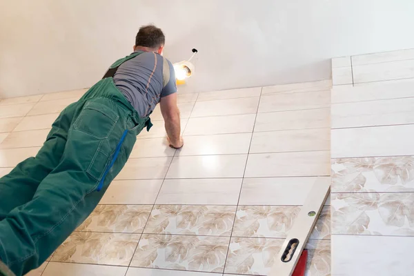 A construction worker applies leveling compound to the ceiling with a stainless steel trowel. Works at height from the ceiling. — Stock Photo, Image