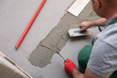 Profesyonel inşaat işçisi seramik fayansları banyoda yere seriyor..