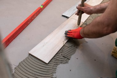 Lastik çekiç. Tecrübeli bir inşaat işçisi. Banyoya terracotta seriyorum. İş kıyafetleri. Çekiçle vuruyor..