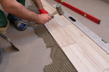 Lastik çekiç. Tecrübeli bir inşaat işçisi. Banyoya terracotta seriyorum. İş kıyafetleri. Çekiçle vuruyor..