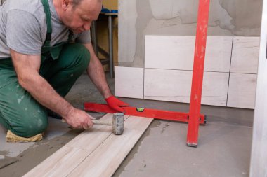 Lastik çekiç. Tecrübeli bir inşaat işçisi. Banyoya terracotta seriyorum. İş kıyafetleri. Çekiçle vuruyor..
