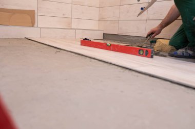 Profesyonel inşaat işçisi seramik fayansları banyoda yere seriyor..