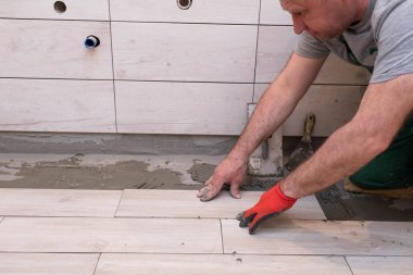 Genel inşaat işçisi. Seramik fayanslar için yapıştırıcı. İnşaatçı yere terracotta yapıştırıyor..