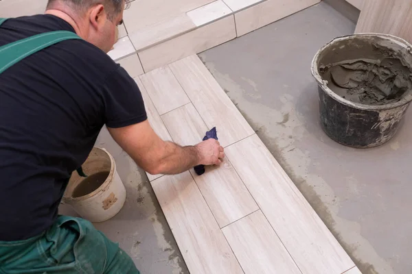 Cleaning the adhesive from ceramic tiles. Construction worker. Bathroom renovation work.