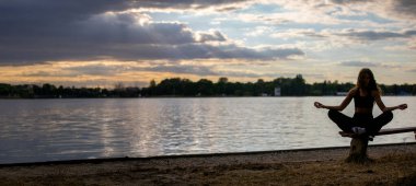 Bir birey, gün batımında suları sakinleştirerek huzur içinde meditasyon yapar. Mükemmel bir sükunet ve farkındalık oluşturur.