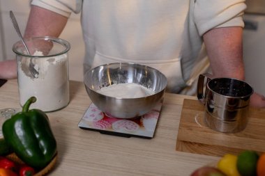 Becerikli bir aşçı modern bir mutfakta kaseler ve taze sebzelerle malzemeleri dikkatlice hazırlar.