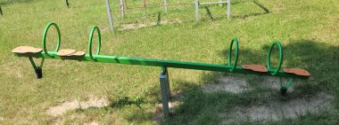 Canlı yeşil bir tahterevalli çimlerin üzerinde çocuklar için harika bir yer sunuyor oyun alanında eğlence ve keyif için.