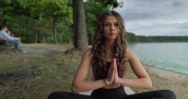Güzel, huzurlu bir manzara. Huzurlu ve sakin bir göl kenarında derin derin meditasyon yapan bir kadın. Etrafı yemyeşil.