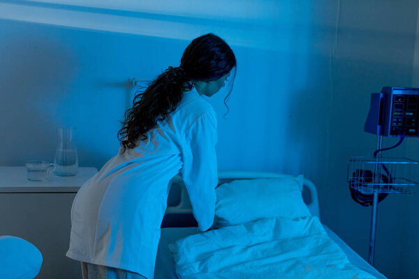 Медицинский работник, заботящийся о пациенте в больничной палате, отражающий глубокую заботу и сострадание