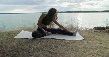 Huzurlu göl kenarında, esneklik ve farkındalığın vurgulandığı sakin ve dingin bir yoga uygulaması gerçekleştiriliyor.