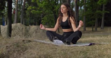 Açık havada meditasyon yapan bir kadın, doğanın rahatlatıcı ve huzurlu güzelliği ile kuşatılmıştır, farkındalığı teşvik eder.