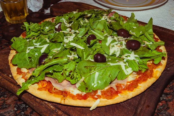 Νόστιμη ορεκτική πίτσα με τυρί, ντομάτες, ρόκα, ελιές, βασιλικό σε ξύλινο τραπέζι — Φωτογραφία Αρχείου