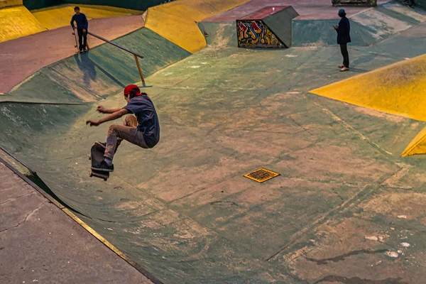Um adolescente de calças e um boné faz uma acrobacia de Aliado em uma rampa em um parque de skate em uma área residencial no verão. O conceito de cultura de skate e lazer juvenil . — Fotografia de Stock
