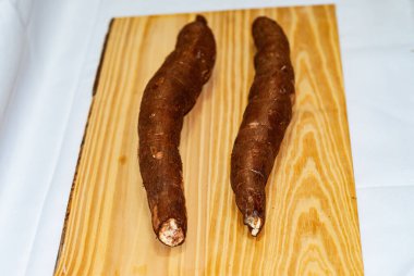 Ahşap masada çiğ yukka, Manihot esculenta. (Cassava çiğ yumrusu) Mandioca, yuca, balinghoy, mogo, mandioca, kamoteng kahoy, tapyoka ve tapyoka kökü olarak da bilinir. Seçici odaklan.