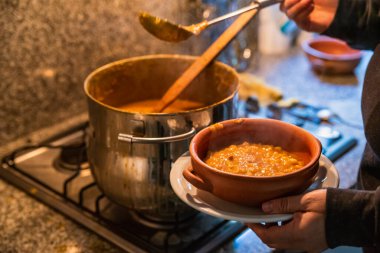 Locro servis eden kadın, tipik Arjantin yemekleri, el yapımı seramik tabaklarda..