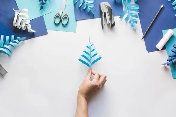 How to make paper beautiful Christmas toy snowflake to decorate room with children. Step by step instructions. Hands making winter DIY. Step 8. Glug following strips on other side. Alternate sides.