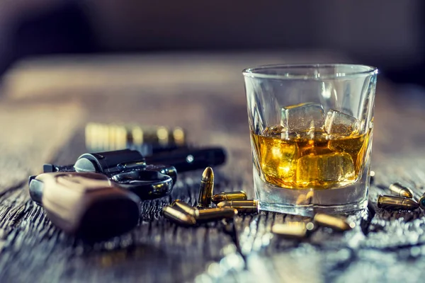 ウイスキー コニャックやバーボンのリボルバーと弾丸木製テーブルの上のガラス — ストック写真