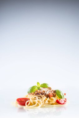 Spagetti bolognese fesleğen domates ve beyaz zemin üzerine parmesan peyniri.