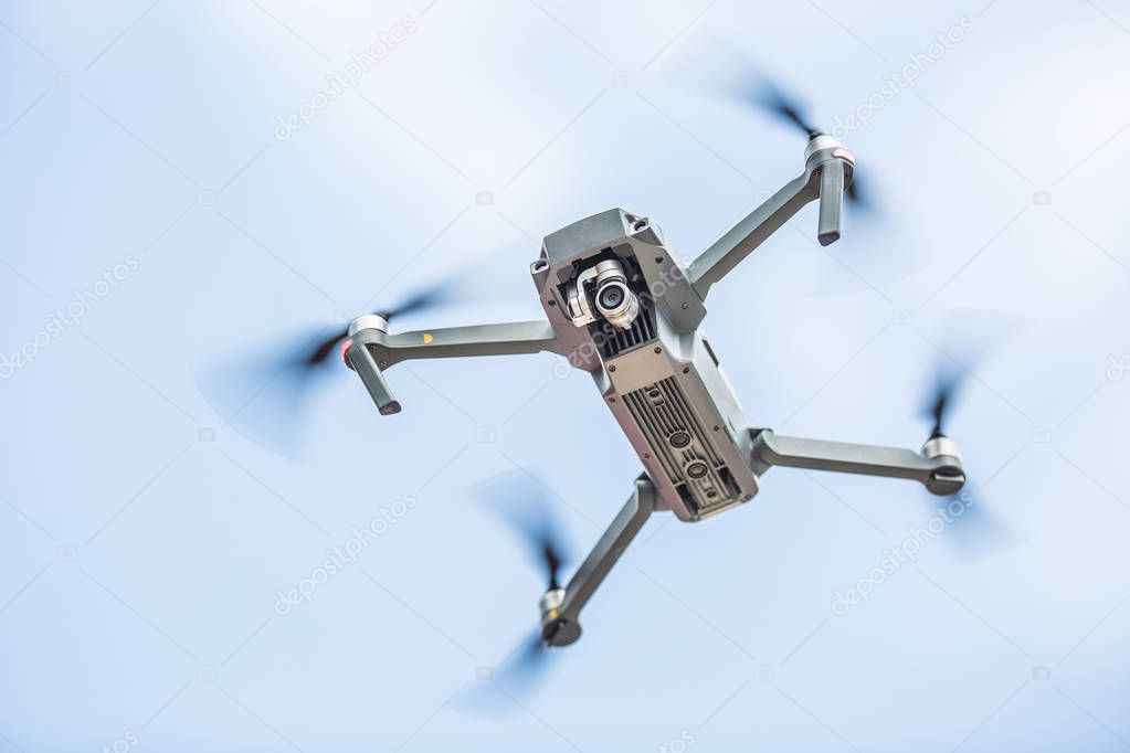 Close-up quadcopter drone with camera flying in park.