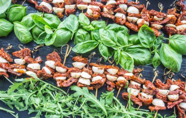 Kurutulmuş domates mozzarella fesleğen ve roka kayrak gemide Caprese salatası.