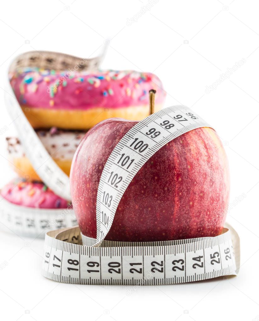 Red apple and three colorful donuts wrapped in a tailors measuring tape isolated on white.
