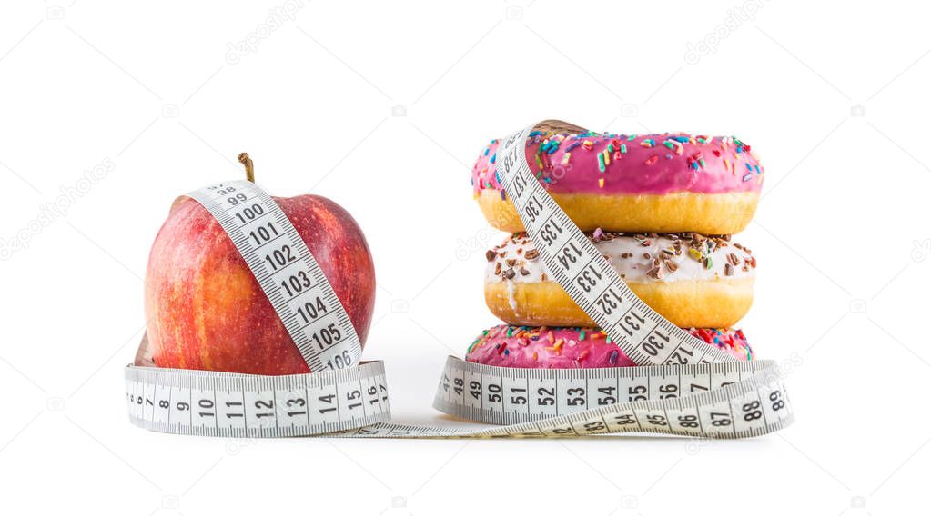 Red apple and three colorful donuts wrapped in a tailors measuring tape isolated on white.