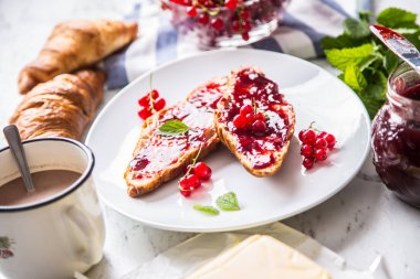 Kırmızı kuş üzümü reçeli kruvasan tereyağı ve nane yaprakları ile lezzetli breakfast.