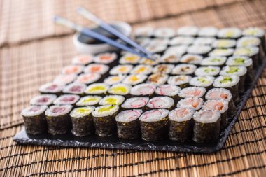 Suşi maki soya sosu ve yemek çubukları ile kayrak gemide topluluğu.