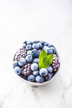 Yakın çekim dondurulmuş yaban mersini ve nane yaprakları ile böğürtlen.