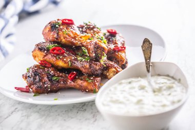 Kavrulmuş ızgara ve Barbekü tavuk budu beyaz plaka ve tzatziki sos.