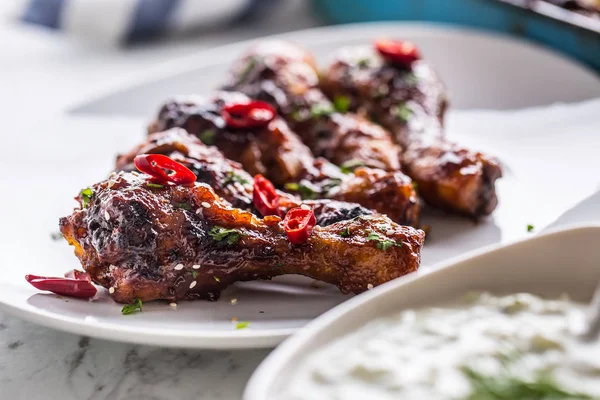 Kavrulmuş ızgara ve Barbekü tavuk budu beyaz plaka ve tzatziki sos.