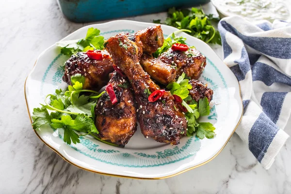 Kavrulmuş ızgara ve Barbekü tavuk budu ot dekorasyonu ile beyaz plaka üzerinde.