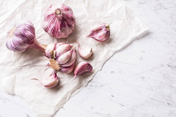 Garlic Cloves and Bulbs on white marble board.