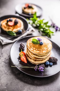 Çilek Böğürtlen yaban mersini lavanta ve nane yaprakları ile Pancakes.