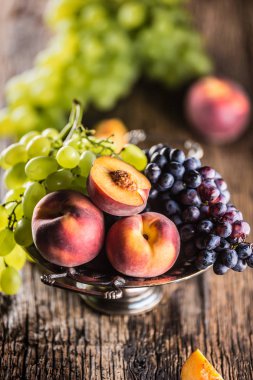 Olgun üzüm ve şeftali rustik kase ve ahşap masa.