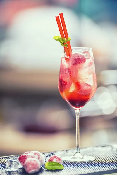 Strawberry lemonade or alcoholic cocktail with ice syrup soda and mint leaves on bar table.