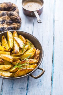 Ahşap tahta üzerinde bir tavada kavrulmuş patates.