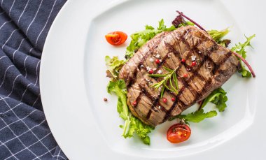 Sulu Külbastı sebze salatası tuz biber ve biberiye beyaz tabakta bölümünü yakın çekim.