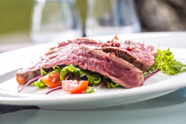 Sulu Külbastı sebze salatası tuz biber ve biberiye beyaz tabakta bölümünü yakın çekim.