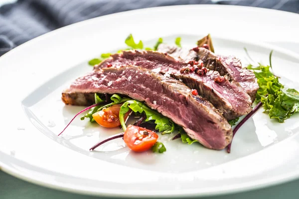 Sulu Külbastı sebze salatası tuz biber ve biberiye beyaz tabakta bölümünü yakın çekim.