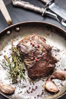 Baharatlar ve otlar eski tavada sulu biftek biftek.