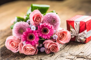 Ahşap masa üzerinde kırmızı hediye ile buket güzel.