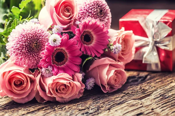美丽的花束与红色礼物在木桌上 — 图库照片