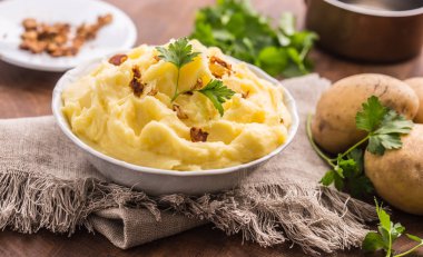 Kase patates püresi maydanoz otlar dekore edilmiş ve kavrulmuş domuz pastırması parçaları.