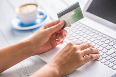 Kredi kartı laptop ve sanat kahve üzerinde arka plan kullanarak tutan el.